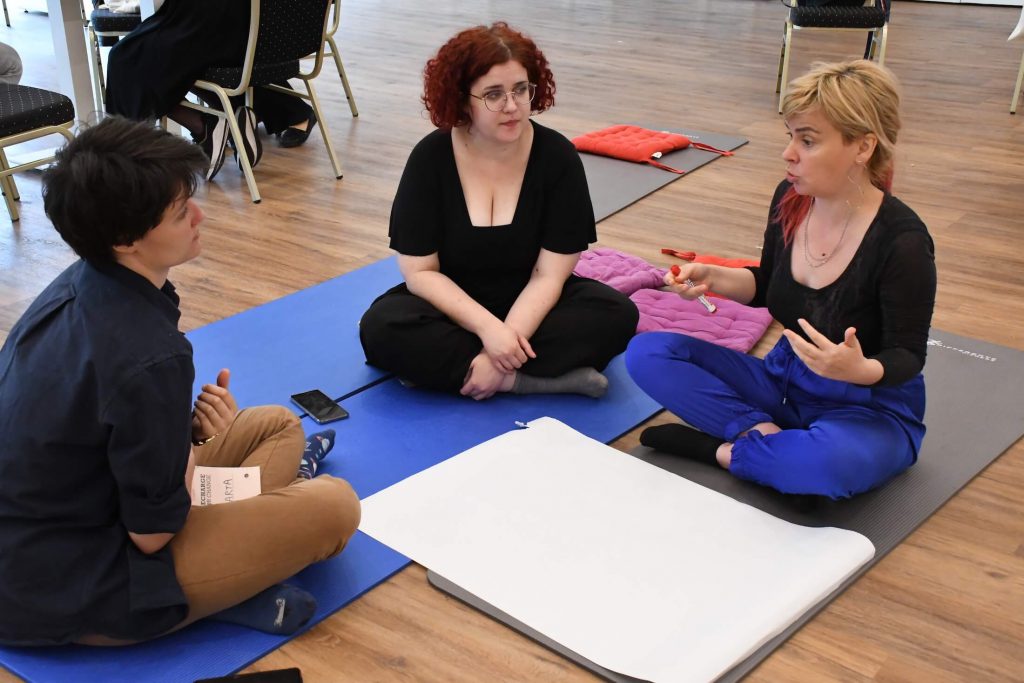 Three participants of the convening in a discussion sitting on the floor